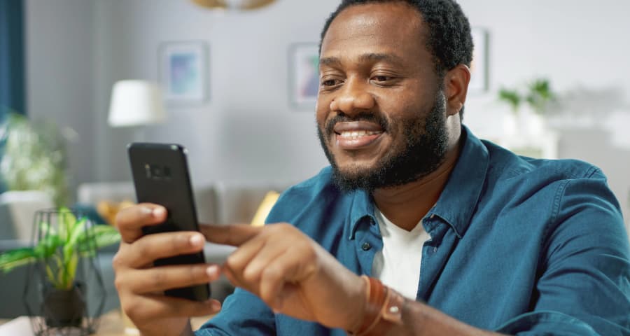 Man sitting down navigating a home security app on his phone